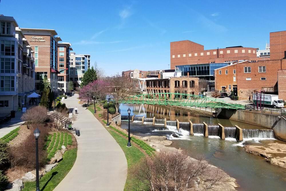 Downtown Greenville, NC, sidewalk along river with green bridge spanning it
