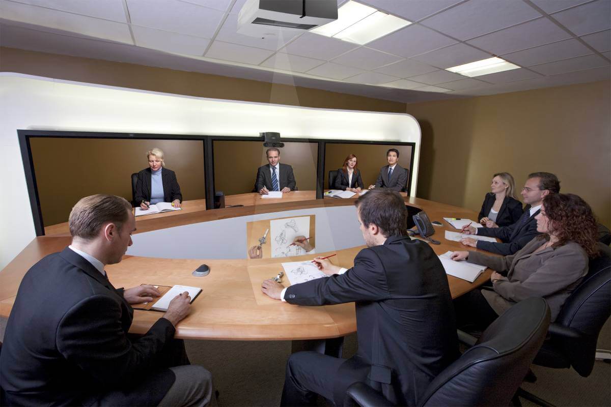 Business people sitting around a table with screens in front of them on a video conference